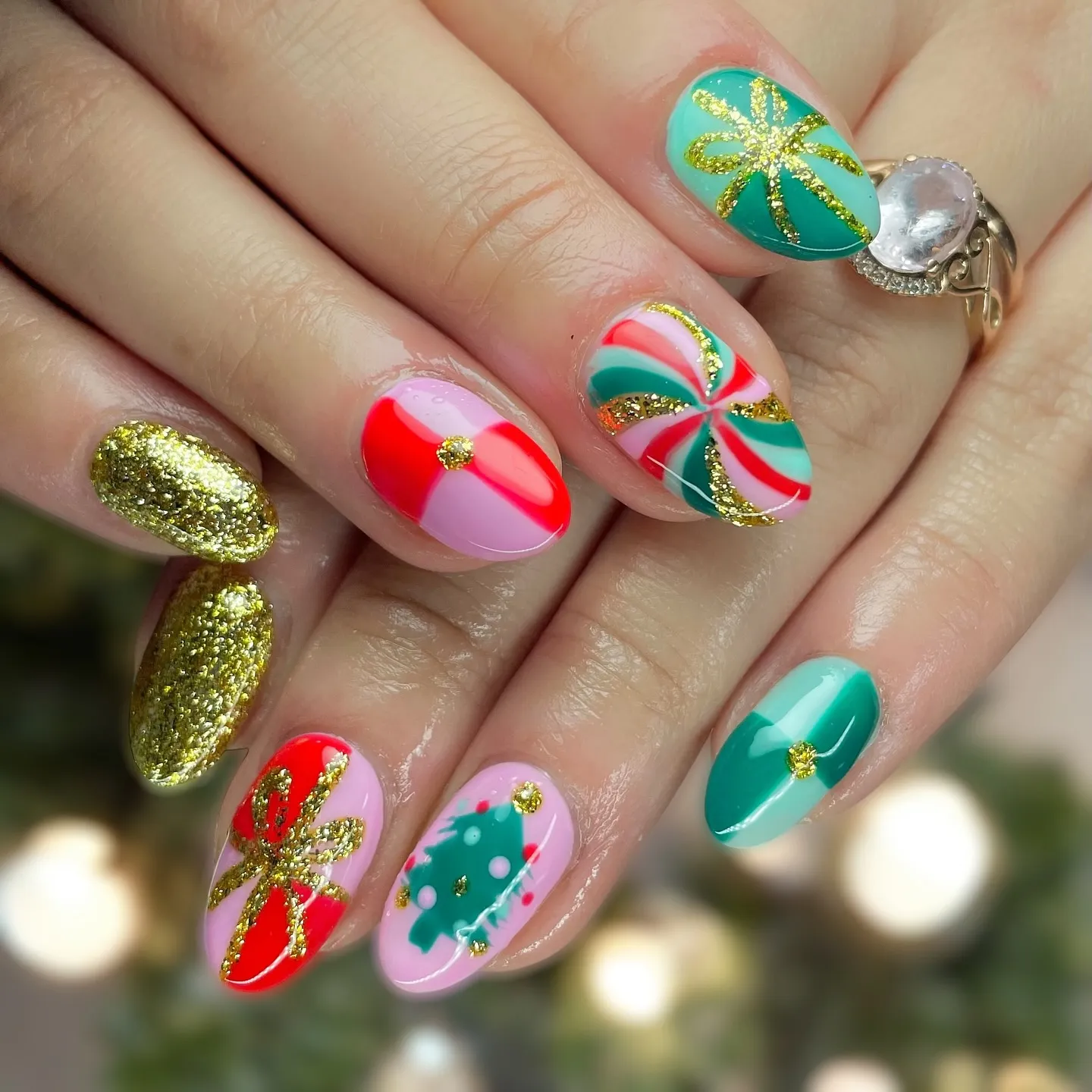 These trendy Christmas nails from @thats.handy_ look like holiday presents come to life. The mix of pink, red, and mint with gold bows and sparkles is perfect if you’re after December nails that are playful yet glam.